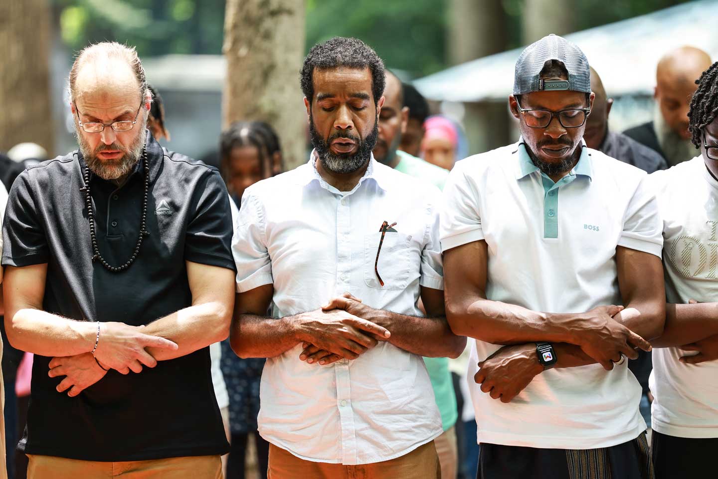 A line of men at an community event sharing time in prayer