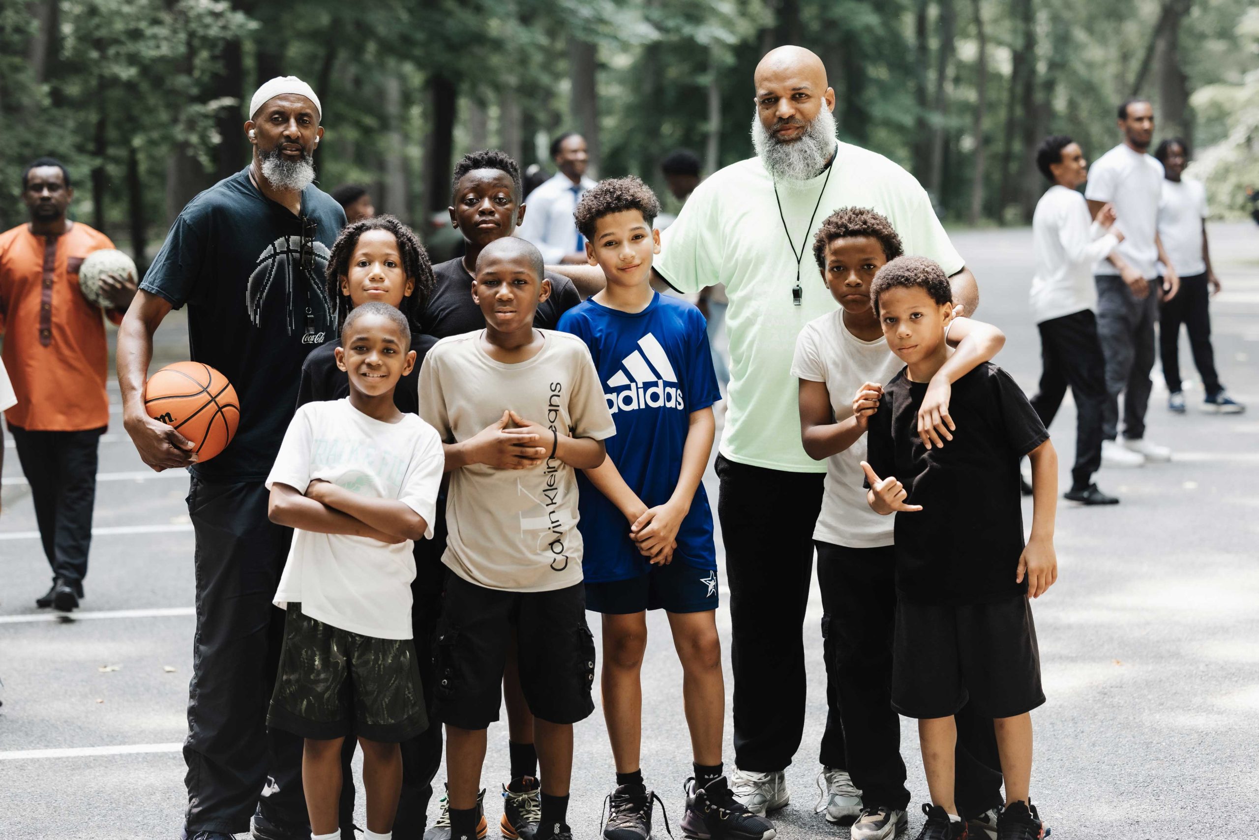 Two coaches posing with a group of young boys after a basketball game
