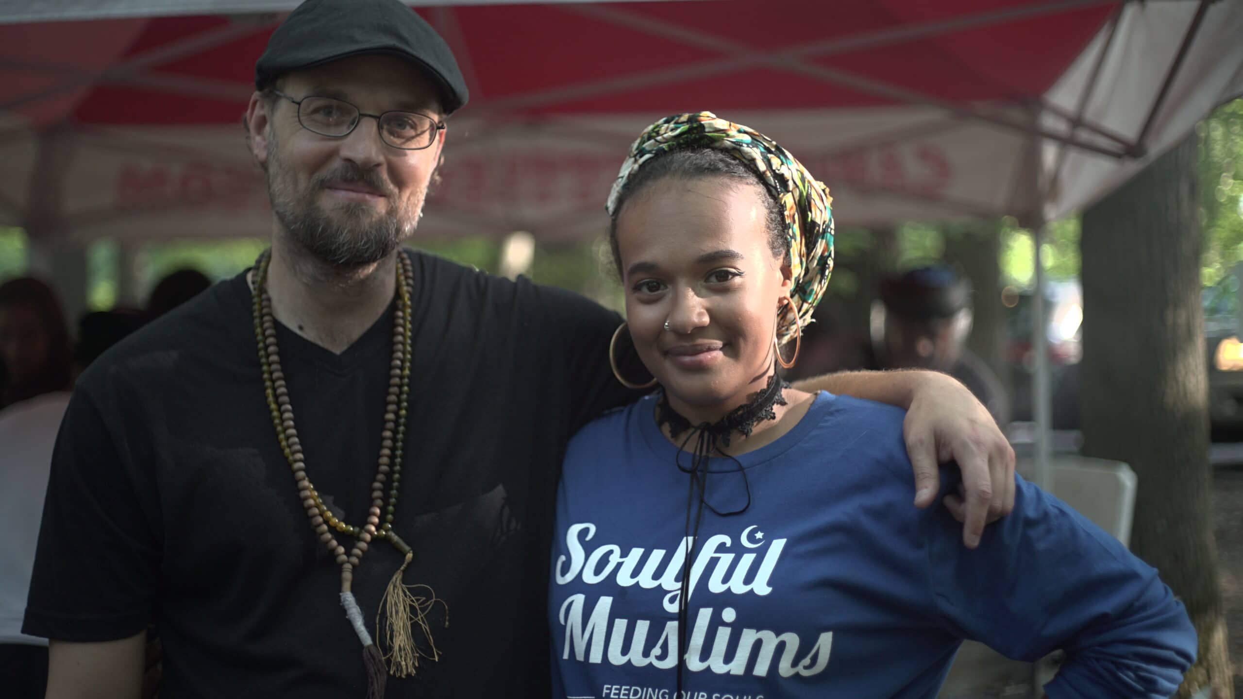 Two community members hugging at an event while smiling at the camera