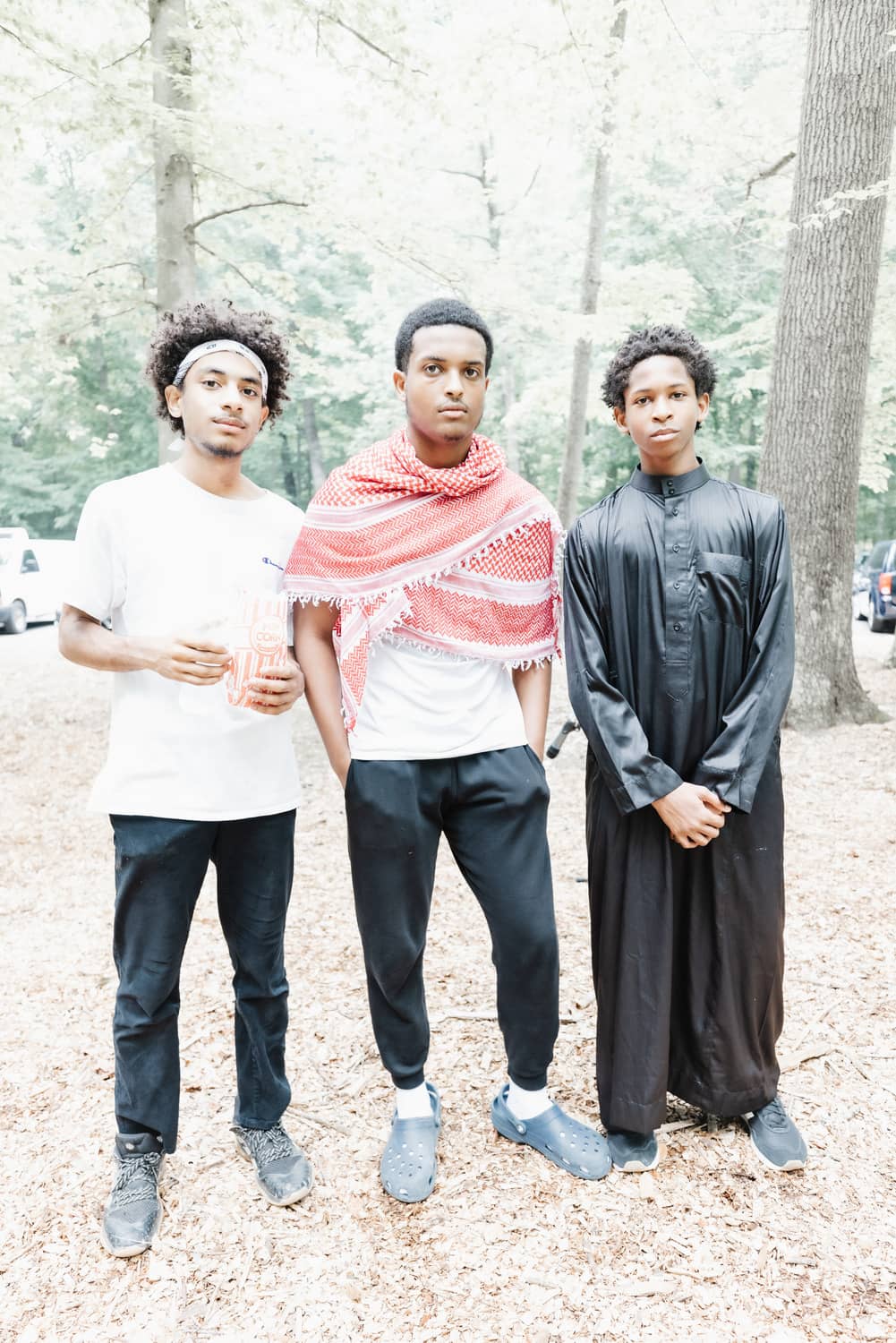 Three young men at Soulful Eid 2023 enjoying popcorn and posing for a picture.